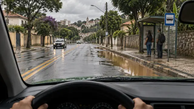 Motorista se aproxima de uma poça junto ao ponto de ônibus onde duas pessoas aguardam.