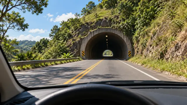 Num dia claro, a estrada entra num túnel aberto através de um morro; do carro vê-se a diferença entre a luz do sol e o trecho coberto.